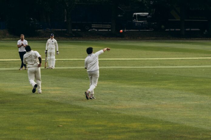 Cricketers on a green field as a bowler delivers, illustrating the Hong Kong Sixes 2026 preview