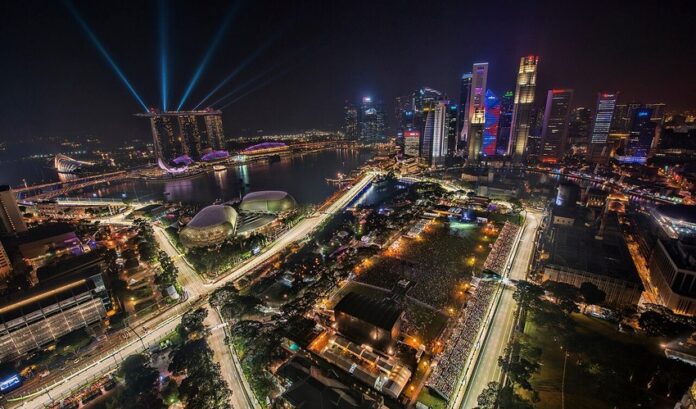 Formula One cars race at night on the Marina Bay Street Circuit with the Singapore skyline behind