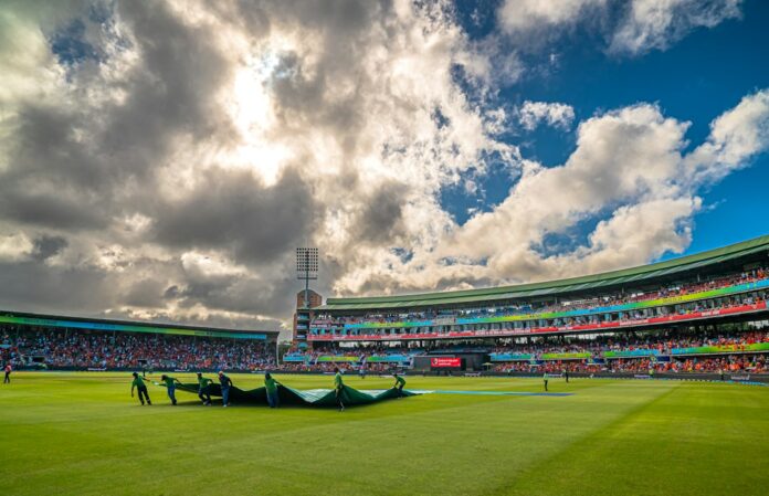 Ground staff cover the pitch at St George's Park cricket ground in Gqeberha, South Africa, under dark clouds