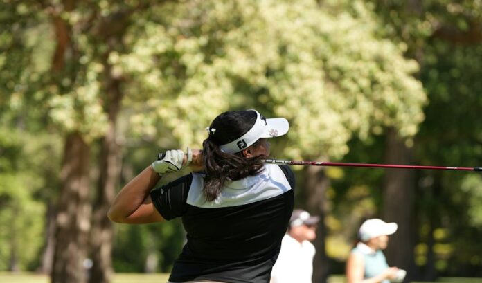 Woman golfer swinging a club on a sunny day A woman golfer swinging her club on a golf course on a sunny day